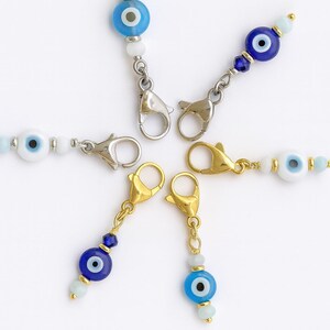 Pu&ograve; includere: Un assortimento di ciondoli di perline con il design dell'occhio diabolico. I ciondoli hanno perline blu e bianche, con un design oculare centrale. Sono attaccati a chiusure metalliche in tonalit&agrave; argento e oro.