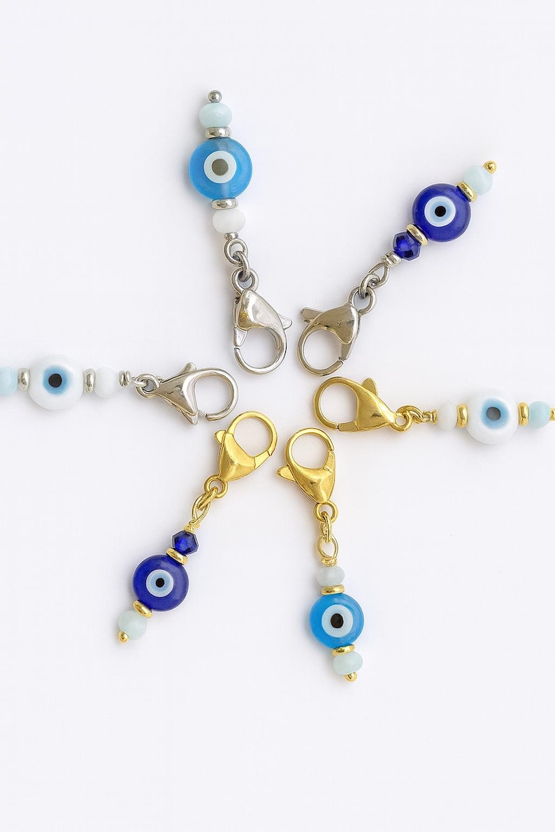 Pu&ograve; includere: Un assortimento di ciondoli di perline con il design dell'occhio diabolico. I ciondoli hanno perline blu e bianche, con un design oculare centrale. Sono attaccati a chiusure metalliche in tonalit&agrave; argento e oro.