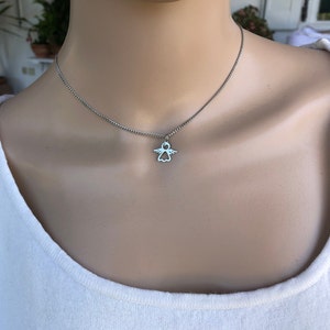 May include: A silver chain necklace with a small angel pendant. The angel is a simple outline with wings and a halo.