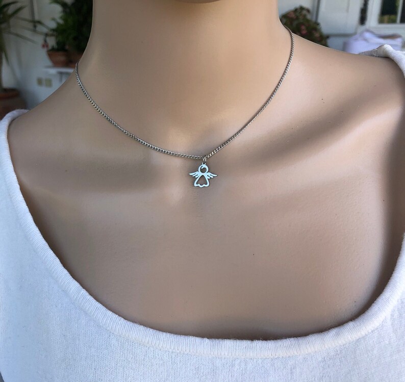 May include: A silver chain necklace with a small angel pendant. The angel is a simple outline with wings and a halo.