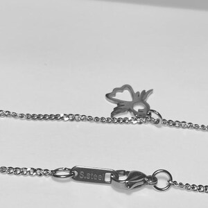 May include: A silver chain necklace with a small, open heart charm and a lobster clasp. The clasp has a tag that reads "S.Steel".