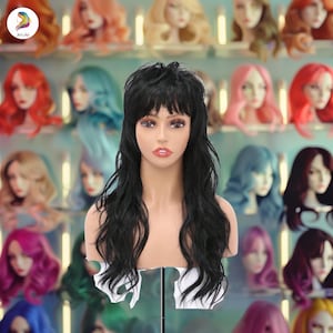 May include: A black wig with long, wavy hair and bangs. The wig is displayed on a mannequin head against a backdrop of colourful wigs.