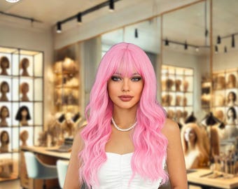 Puede incluir: Una mujer con una peluca rosa larga y ondulada con flequillo y un collar de perlas. La peluca tiene un aspecto natural y está peinada con rizos sueltos. El fondo es una peluquería con pelucas en exhibición.