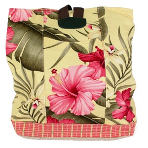 Puede incluir: Una bolsa de lona amarilla con estampado floral rosa y verde. La bolsa tiene una correa marrón y un ribete de rayas rojas y blancas.