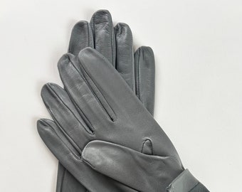 May include: A pair of gray leather gloves with a suede cuff. The gloves are folded in half and the cuff is visible.