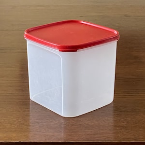 May include: A white ceramic mug with a black handle and the text "But First, Coffee" in a bold, black font. The mug is set against a blurred background, suggesting a cozy setting.