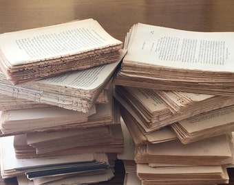 以下が含まれることがあります： 古書と思われるページが積み重なった写真。オフホワイトの紙面には活字が印刷され、ざらつきのある質感と不揃いな縁が、古き良き時代の雰囲気を醸し出しています。