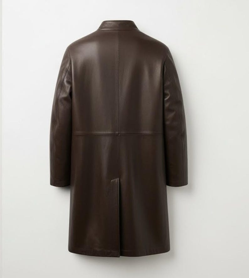 May include: A dark brown leather coat with a classic design. The coat has a notched collar, long sleeves, and a knee-length hem. The back of the coat features a center vent for ease of movement. The coat is made of a smooth, supple leather.