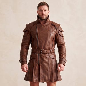 May include: A brown leather coat featuring a high collar, an asymmetrical front zipper, and structured shoulder panels. The garment includes a waist belt with a metal buckle, long sleeves with buckled cuffs, and a pleated skirt-like lower section.