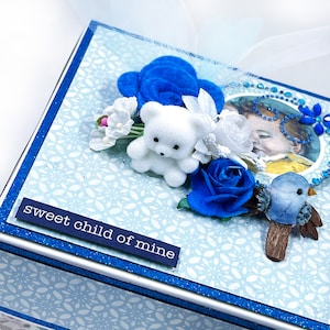 May include: A blue and white baby shower card with a white teddy bear, blue flowers, and the text "sweet child of mine".
