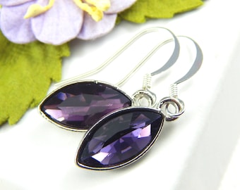 May include: A pair of silver dangle earrings with a marquise-shaped purple crystal.