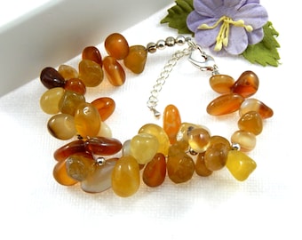 May include: A bracelet made of carnelian and citrine gemstones in shades of orange, yellow, and brown. The bracelet is made with a silver chain and clasp.