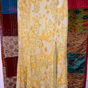 Pode incluir: Uma saia de estampa floral amarela e verde com uma fenda lateral. A saia &eacute; de comprimento at&eacute; o joelho e tem cintura ajustada.