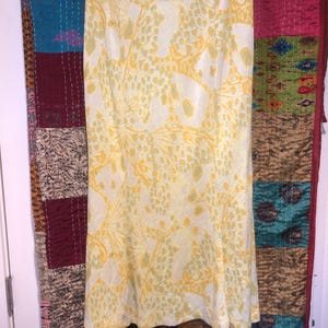 Pode incluir: Uma saia de estampa floral amarela e branca com cintura alta e comprimento midi.