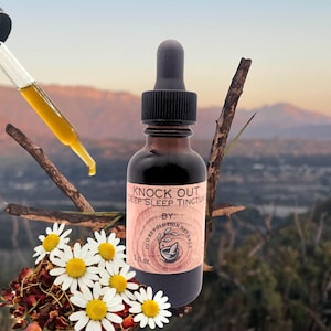 May include: A brown glass bottle of "Knock Out Deep Sleep Tincture" with a black dropper. The label includes the text "Old Revolution Herbs". A dropper with yellow liquid is visible. White daisies and a mountain backdrop complete the image.