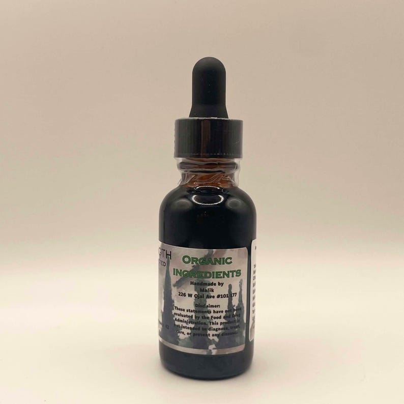May include: A small, dark glass bottle with a black dropper top. The bottle contains a dark liquid and has a label with the words "ORGANIC INGREDIENTS" and other text. The bottle is on a white background.