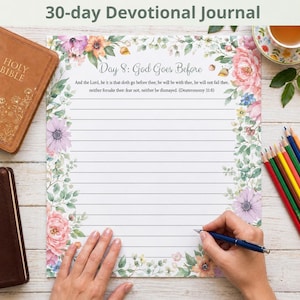 Op de afbeelding: Een gelinieerd dagboek met bloemenrand en de tekst "Day 8: God Goes Before". Het dagboek is open, met een hand die een pen vasthoudt. Een bijbel en kleurpotloden zijn ook zichtbaar.