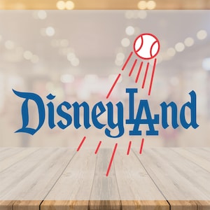 May include: A graphic featuring the text "Disneyland" in a stylized blue font, with "LA" in a similar font. A baseball with red lines is above the text. The background is blurred, with a wooden table in the foreground.