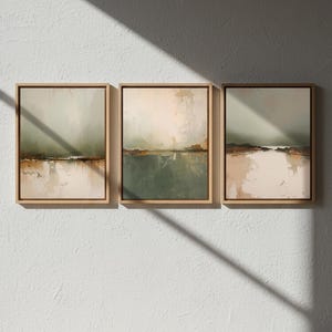 May include: Three framed abstract landscape paintings. Each piece features a muted color palette with earthy tones of green, brown, and beige. The artwork is displayed on a white wall, with a shadow cast across the surface.