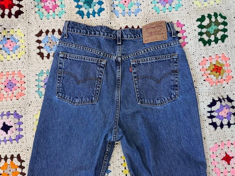 May include: A pair of blue denim jeans with a brown leather patch on the back that says "Levi Strauss & Co. Quality Clothing." The patch also has the text "552" and "W 31 L 34".