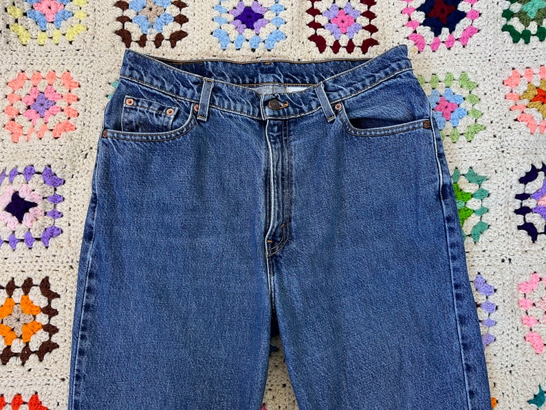 May include: A pair of blue denim jeans with a classic five-pocket style. The jeans have a high waist and a straight leg.