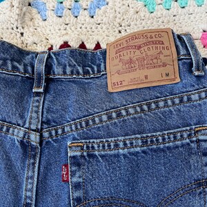 May include: Blue denim jeans with a Levi's label on the back pocket. The label reads "Levi Strauss & Co. Original Riveted Quality Clothing" and "512" Slim Fit Straight Leg.