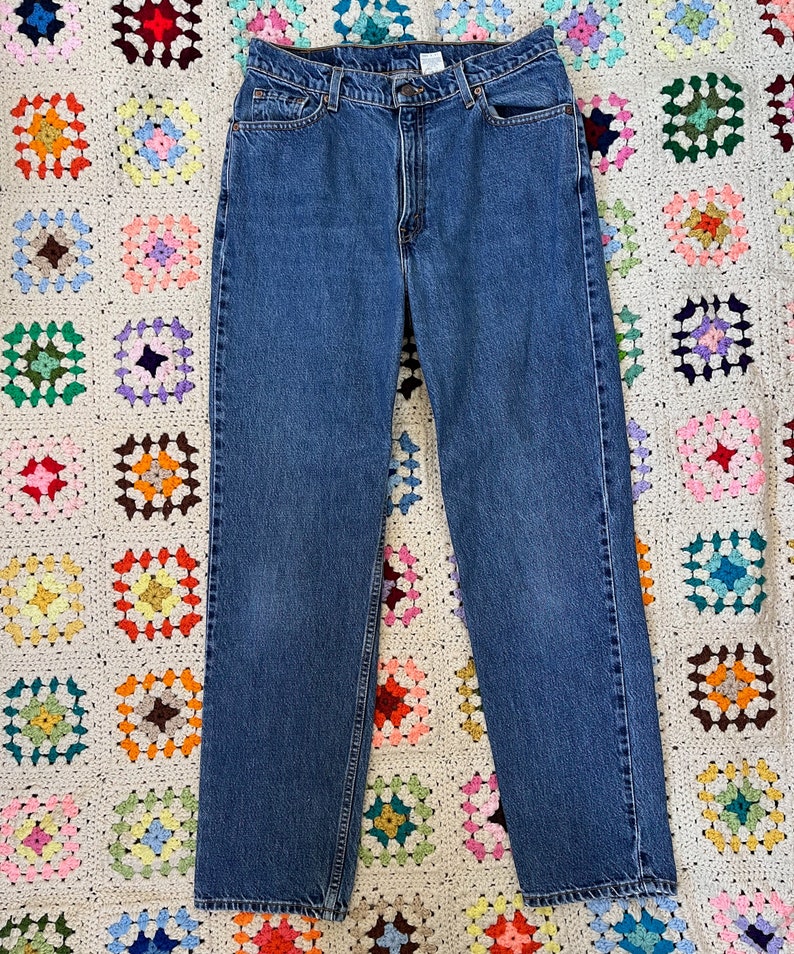 May include: A pair of blue denim jeans with a straight leg fit. The jeans have a classic five-pocket style and a button fly.