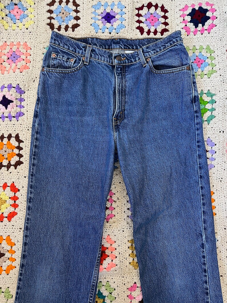 May include: A pair of blue denim jeans with a classic five-pocket style. The jeans have a straight leg and a slightly faded wash.