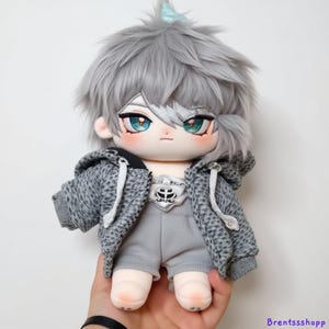 May include: A plush toy with gray hair, a gray hoodie, and gray shorts. The toy has blue eyes and a light blue bow on its head.