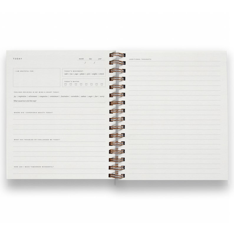 May include: Open journal with lined pages and a spiral binding. The left page features prompts for gratitude, feelings, and daily experiences. The right page offers space for additional thoughts. The journal is designed for daily reflection and self-assessment.