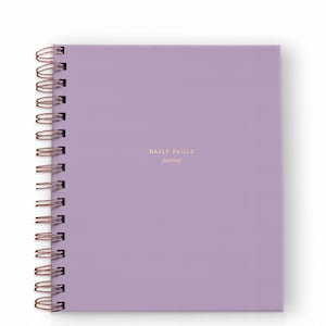 May include: A square, lavender-colored journal with a copper spiral binding. The words "DAILY PAUSE journal" are printed in gold on the front cover. The journal is new and unused.