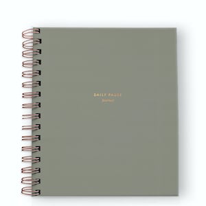 May include: A square, sage green journal with the words "DAILY PAUSE journal" in gold lettering. The journal has a copper-colored spiral binding along the left edge.