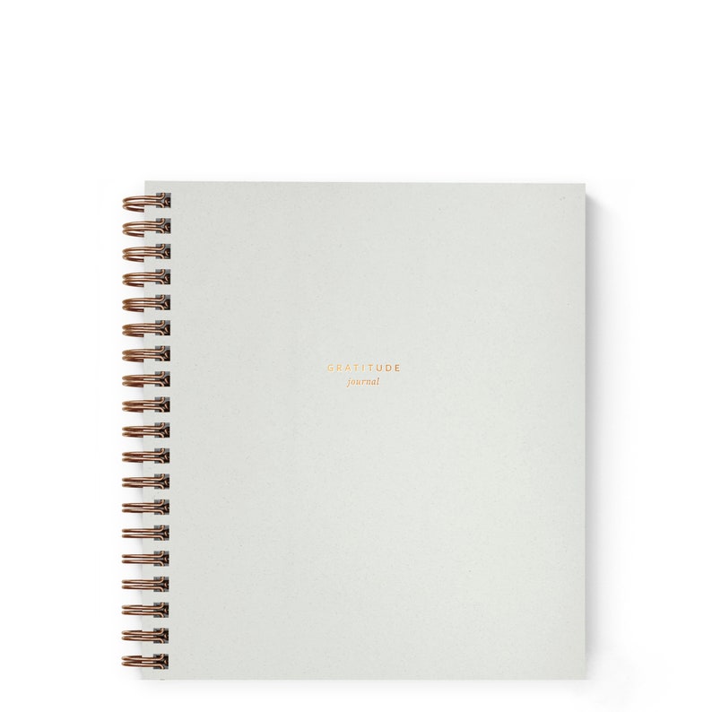May include: A white spiral bound journal with the text "GRATITUDE journal" printed in gold on the front cover.