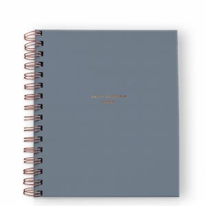 May include: A slate blue spiral-bound planner with copper-colored wire binding. The front cover features the text "DAILY OVERVIEW planner" printed in small, centered copper lettering. The planner has a solid, matte-finish cover.