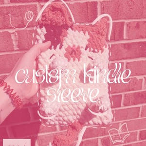 May include: A handmade, crochet Kindle sleeve in the shape of a cat, featuring red and white yarn. The sleeve has a handle and a tail. The text "custom kindle sleeve" is displayed on the front. The logo for "stitch crafts crochet" is in the lower left corner.