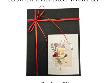 May include: A black gift box tied with a red ribbon, with a small card featuring a floral arrangement and the words "THANK YOU". The text "YOUR GIFT, ALREADY WRAPPED" and "Ready to Gift" are also visible.