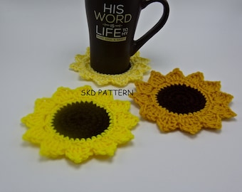 May include: Three crocheted sunflower coasters in yellow and brown. The coasters are on a white surface. The text "SKD PATTERN" is visible in the centre of the image.