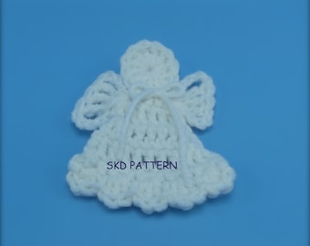Puede incluir: Adorno de ángel blanco tejido a crochet con falda en forma de campana y alas. El adorno tiene una cuerda blanca atada alrededor de la cintura. El texto "SKD PATTERN" es visible en el adorno.