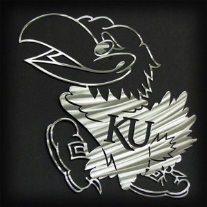 May include: A silver metal wall art sculpture of the University of Kansas mascot, a cartoonish bird with a beak and legs, holding a football. The mascot is wearing a jersey with the letters "KU" on the front.