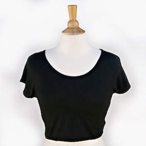 May include: A black cropped t-shirt with short sleeves and a scoop neck.