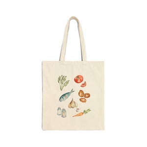 May include: A white canvas tote bag with a design of various food items, including a fish, tomato, garlic, carrots, and potatoes. The design is in a watercolor style.
