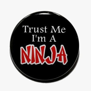 May include: Black button with white text that reads "Trust Me I'm A" and red text that reads "NINJA".