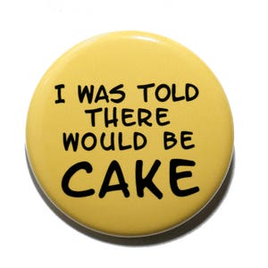 May include: Yellow button with black text that reads "I was told there would be cake."