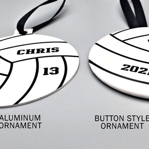 May include: Two volleyball-themed Christmas ornaments, one with an aluminum finish and the other with a button-style finish. Both ornaments feature a black and white volleyball design with the text "CHRIS 13" and "2021" on them.