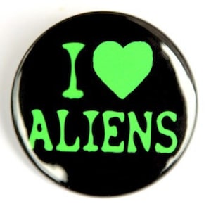 May include: A black button with a green heart and the text "I LOVE ALIENS" in green.
