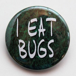 May include: A green and black button with the text "I EAT BUGS" in white.