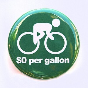 May include: Green round button with a white silhouette of a person riding a bicycle. The text "$0 per gallon" is printed below the bicycle.