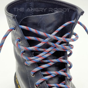 May include: Black leather boots with red, white, and blue shoelaces. The laces are tied in a criss-cross pattern.