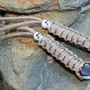 May include: Two tan paracord keychains with skull beads and black heart-shaped end caps.