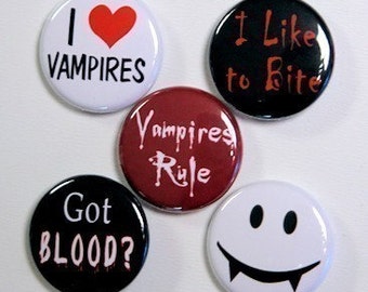 May include: Five round buttons with various vampire-themed designs. The buttons are white, black, and red with black text. The text on the buttons reads "I love vampires", "It like to bite", "Vampires Rule", "Got Blood?", and a smiley face with fangs.